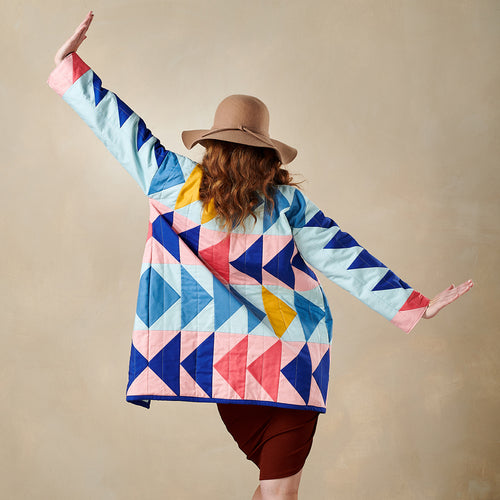 Person wearing a colorful geometric-patterned jacket against a beige background