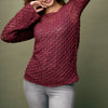 Person wearing a maroon ccrochet sweater against a green background