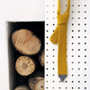 A knitted tie with a solid yellow body and a grey tip, displayed on a pegboard next to wooden logs.