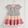 Crocheted dress with a gradient from gray to pink on a wooden background
