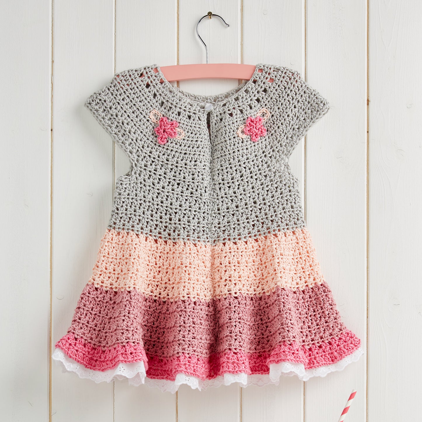 Crocheted dress with a gradient from gray to pink on a wooden background