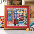 Framed cross-stitch art of a toy shop scene with two children in front.