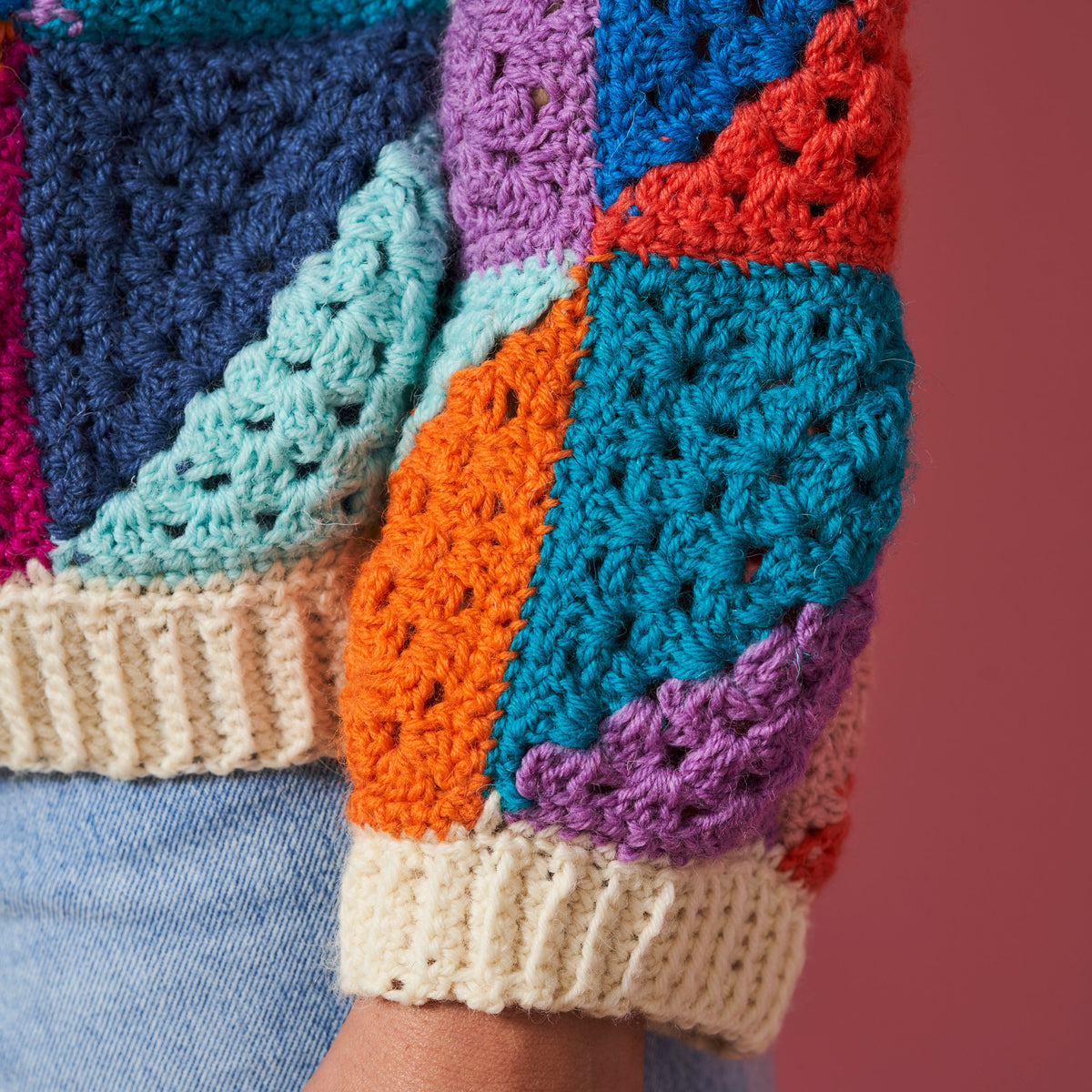 Colorful crochet patchwork sleeve with a pink background