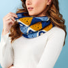 Woman wearing a colorful crochet scarf against a blue background