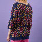 Person wearing a colorful crochet sweater against a purple background