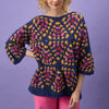 Woman wearing a colorful patterned sweater against a purple background
