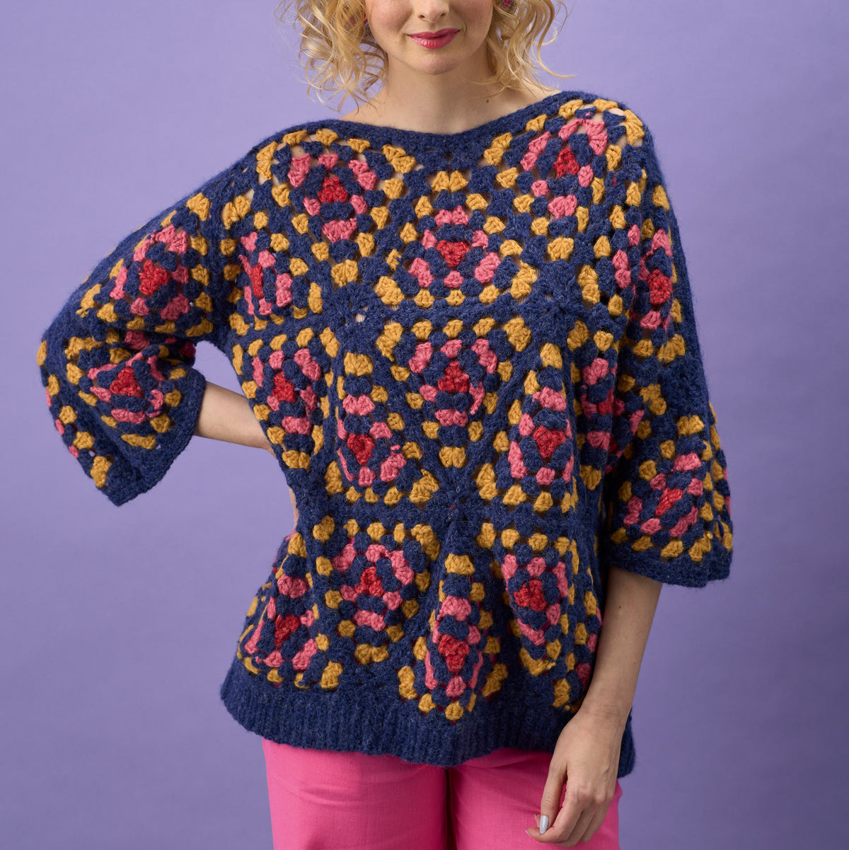 Woman wearing a colorful patterned sweater against a purple background