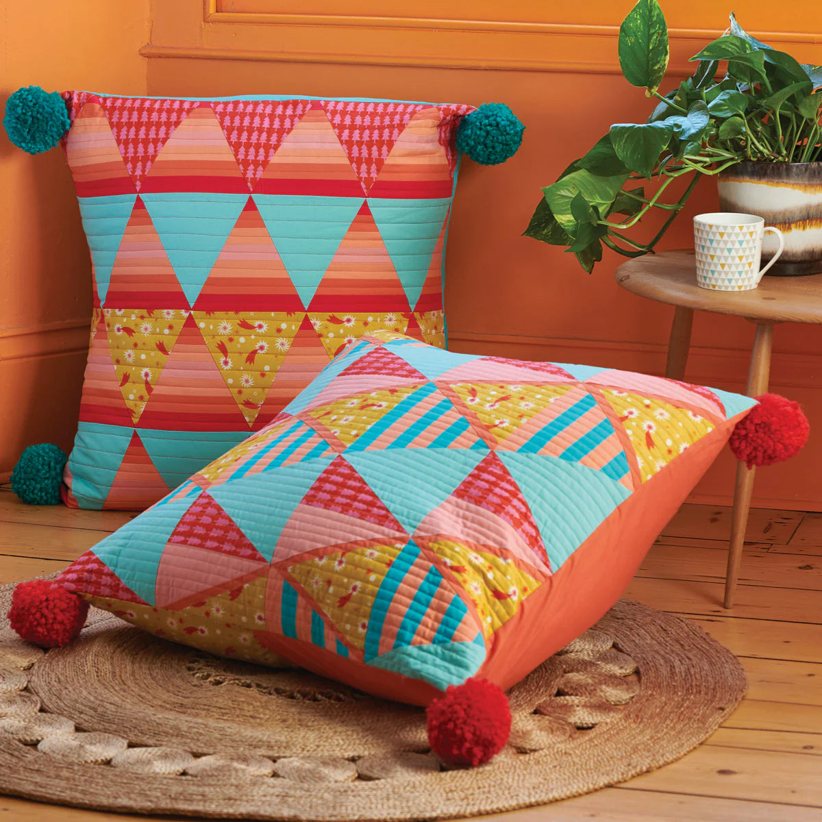 Colorful geometric-patterned cushions with pom-poms on a wooden floor.