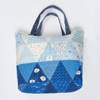 Patchwork tote bag with blue and white patterns on a light gray background