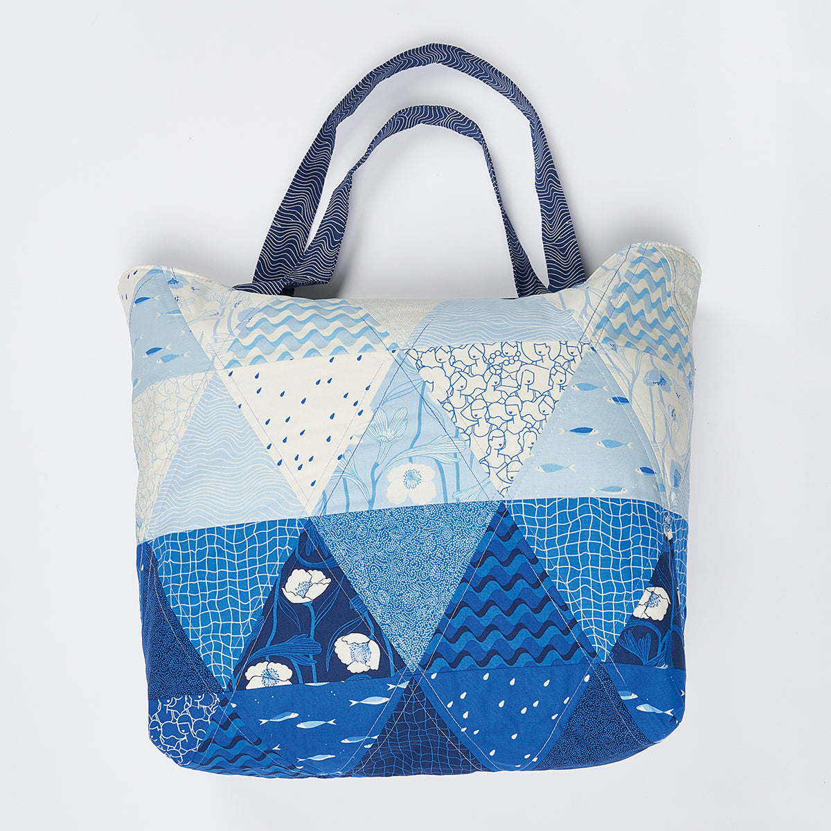 Patchwork tote bag with blue and white patterns on a light gray background