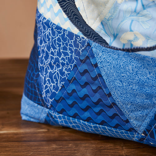 Close-up of a blue quilt with wavy pattern on a wooden surface