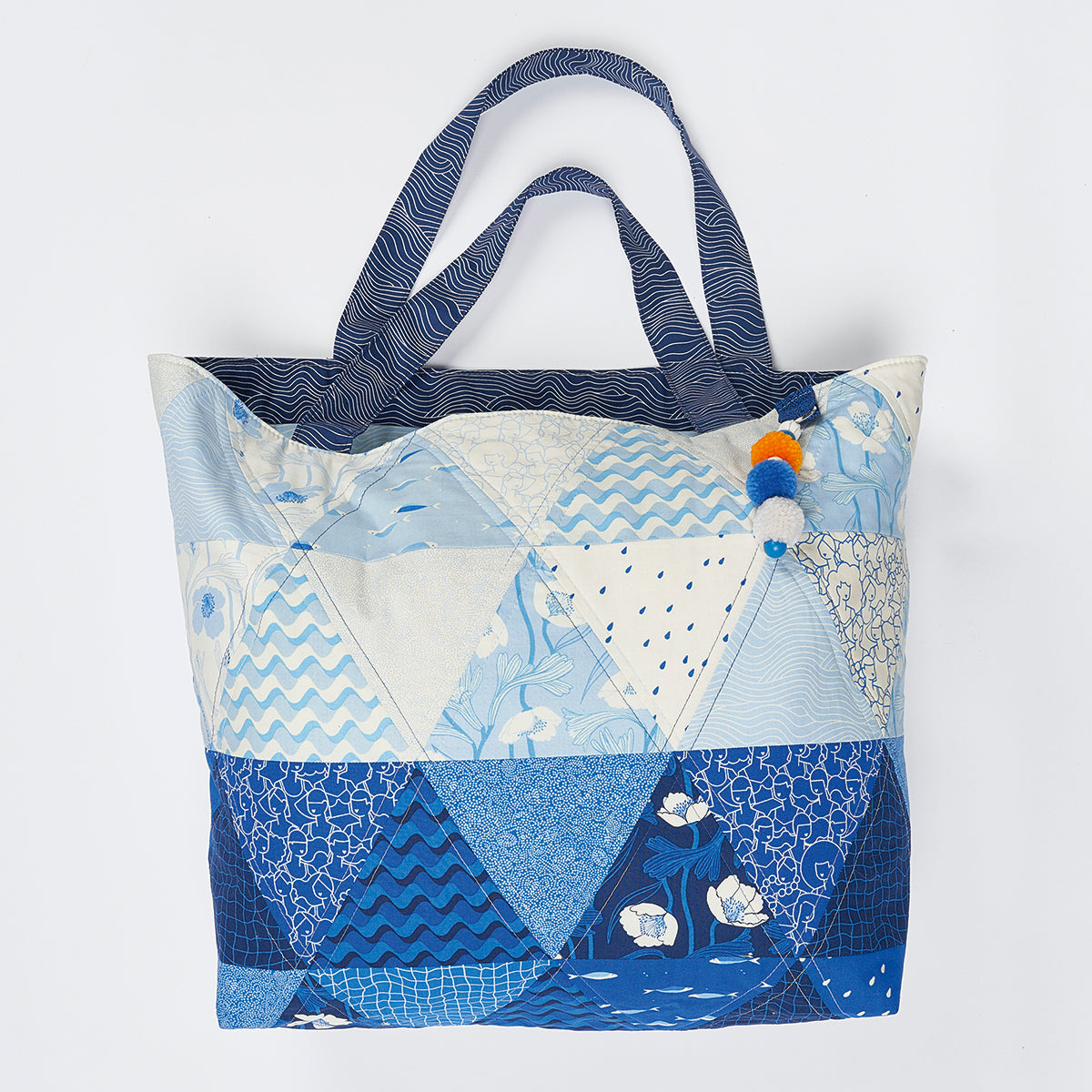 Patchwork tote bag with blue and white patterns on a light gray background