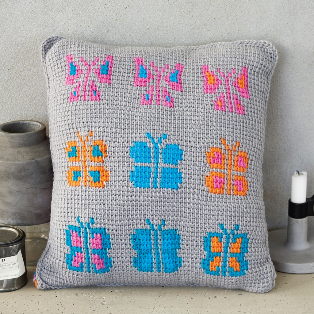 Gray pillow with colorful butterfly patterns on a neutral background