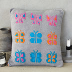 Gray pillow with colorful butterfly patterns on a neutral background