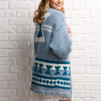 Person wearing a blue and white patterned cardigan against a white brick wall.