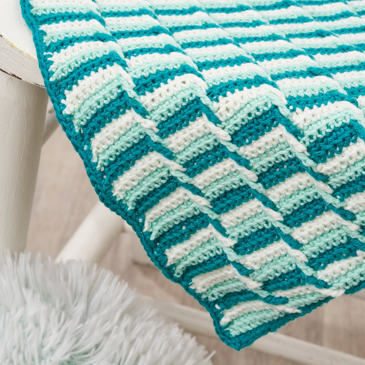 Crocheted blanket with blue and white pattern on a white surface