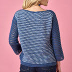 Blue crochet sweater worn by a person on a pink background