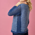 Blue crochet cardigan worn by a person on a pink background