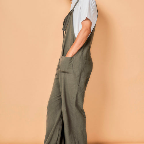 Person wearing green overalls against a beige background