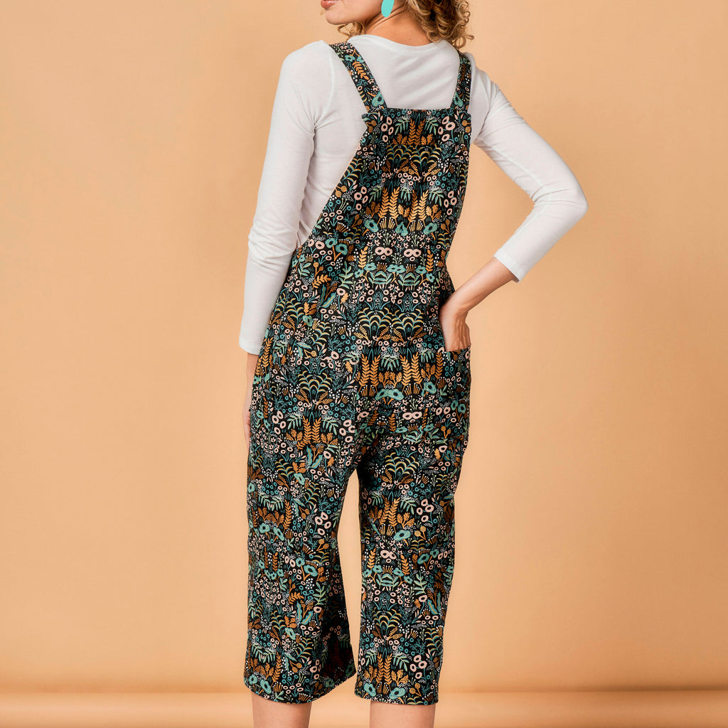 Person wearing a patterned overalls on a beige background