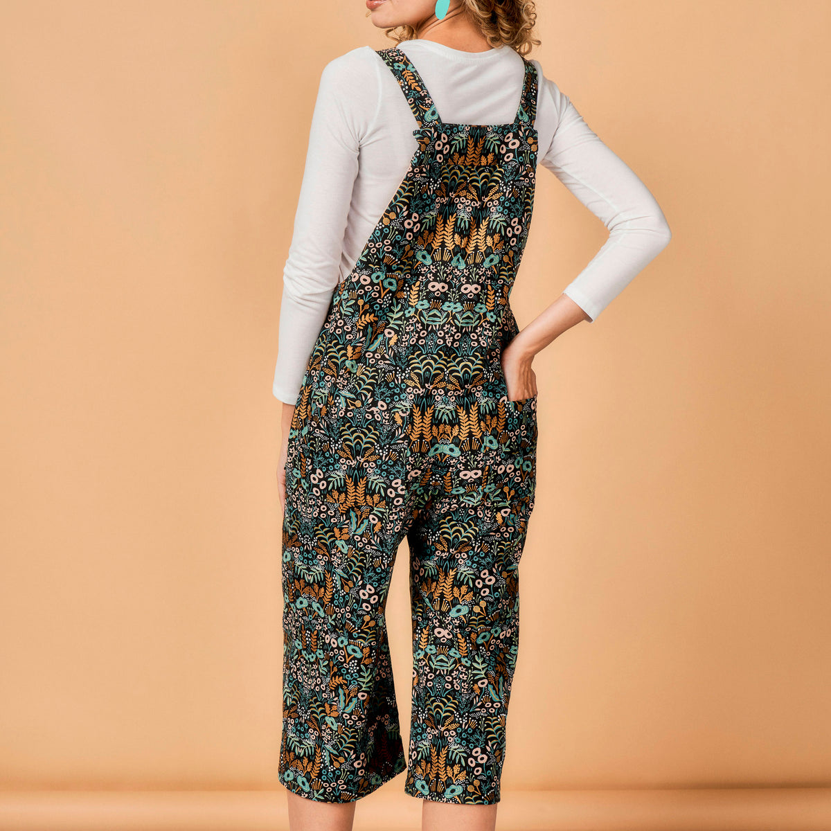 Person wearing a patterned overalls on a beige background