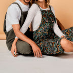 Two people wearing floral aprons sitting on a light-colored floor.