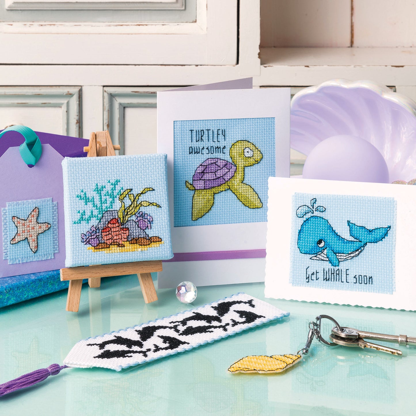 Cross-stitch kits with sea-themed designs on a table.
