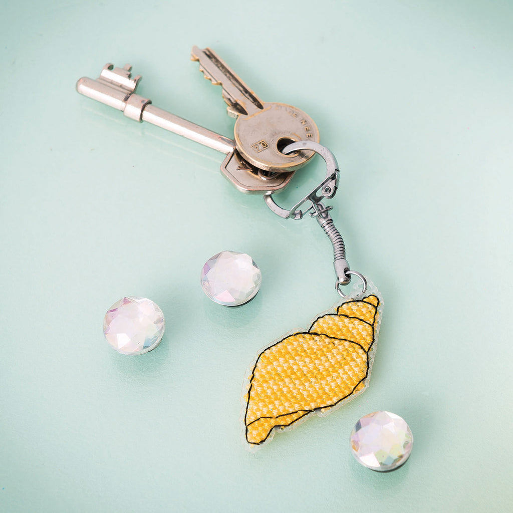 Keychain with a yellow shell charm on a light blue background
