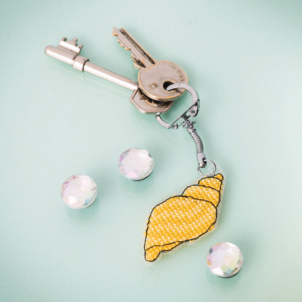 Keychain with a yellow shell charm on a light blue background