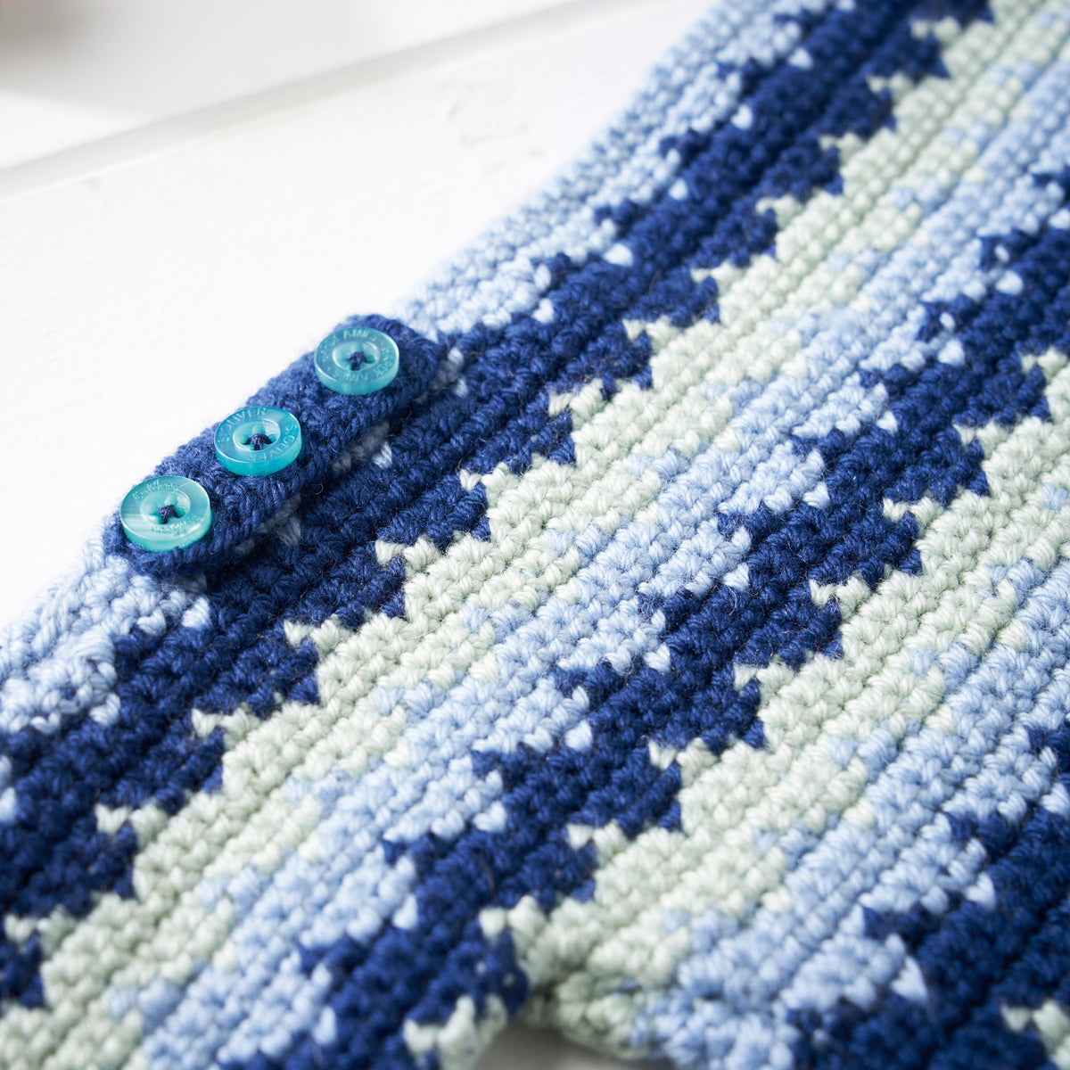 Close-up of a blue and white patterned fabric with buttons on a white background