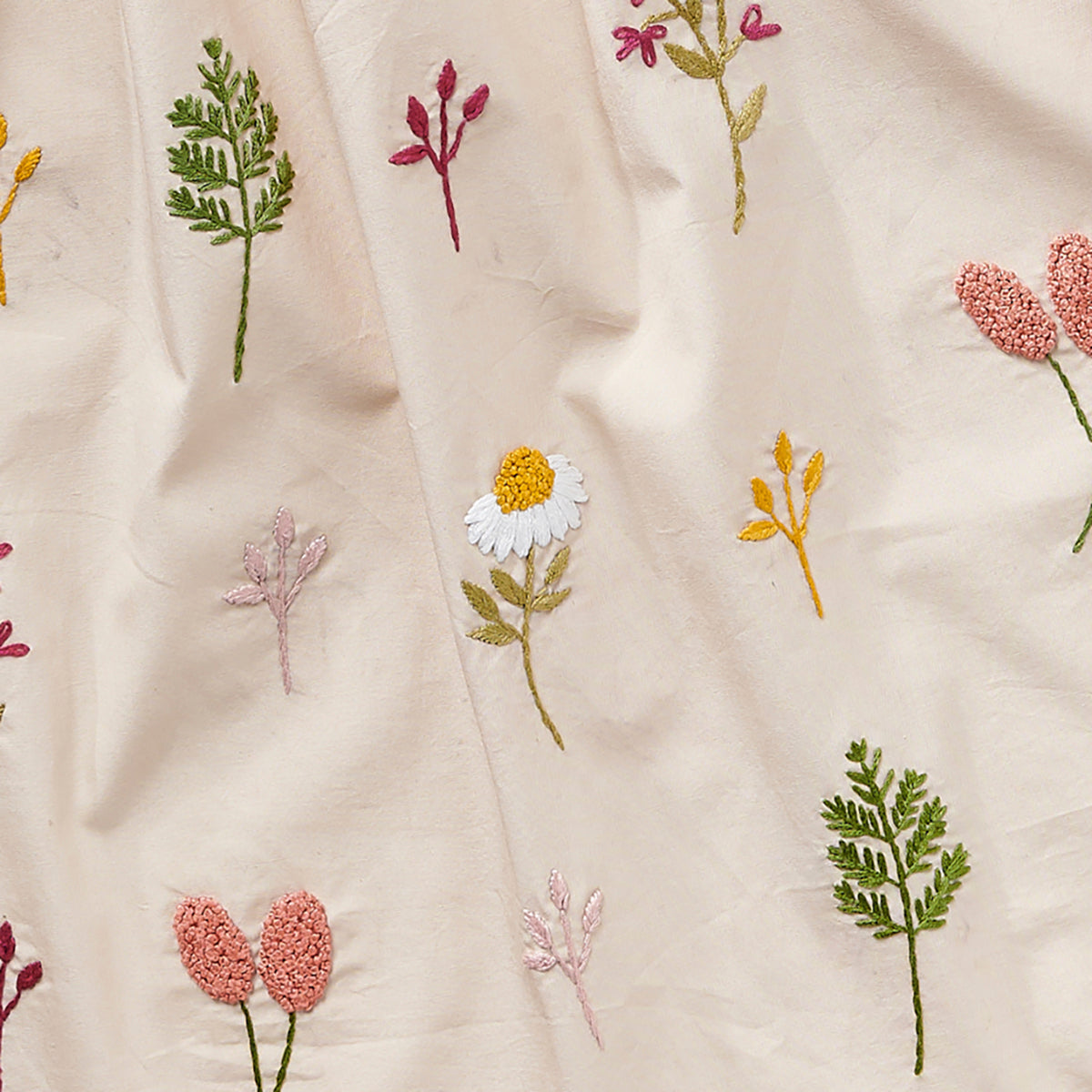 Embroidered pattern of flowers and leaves on a beige fabric background