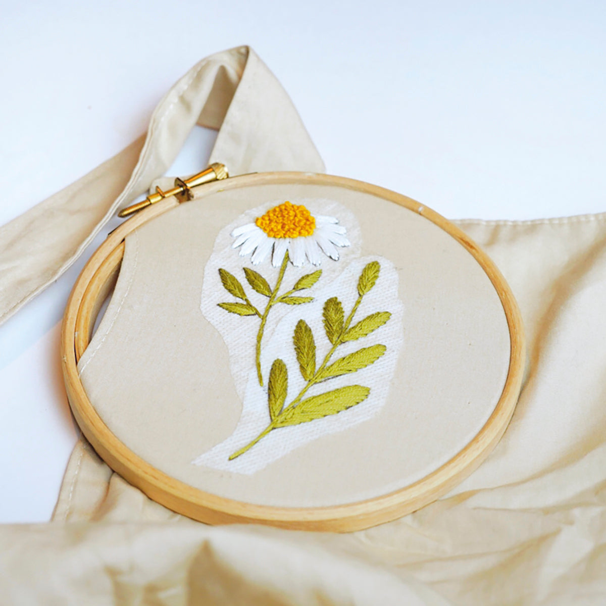 Embroidery hoop with floral design on a beige fabric background