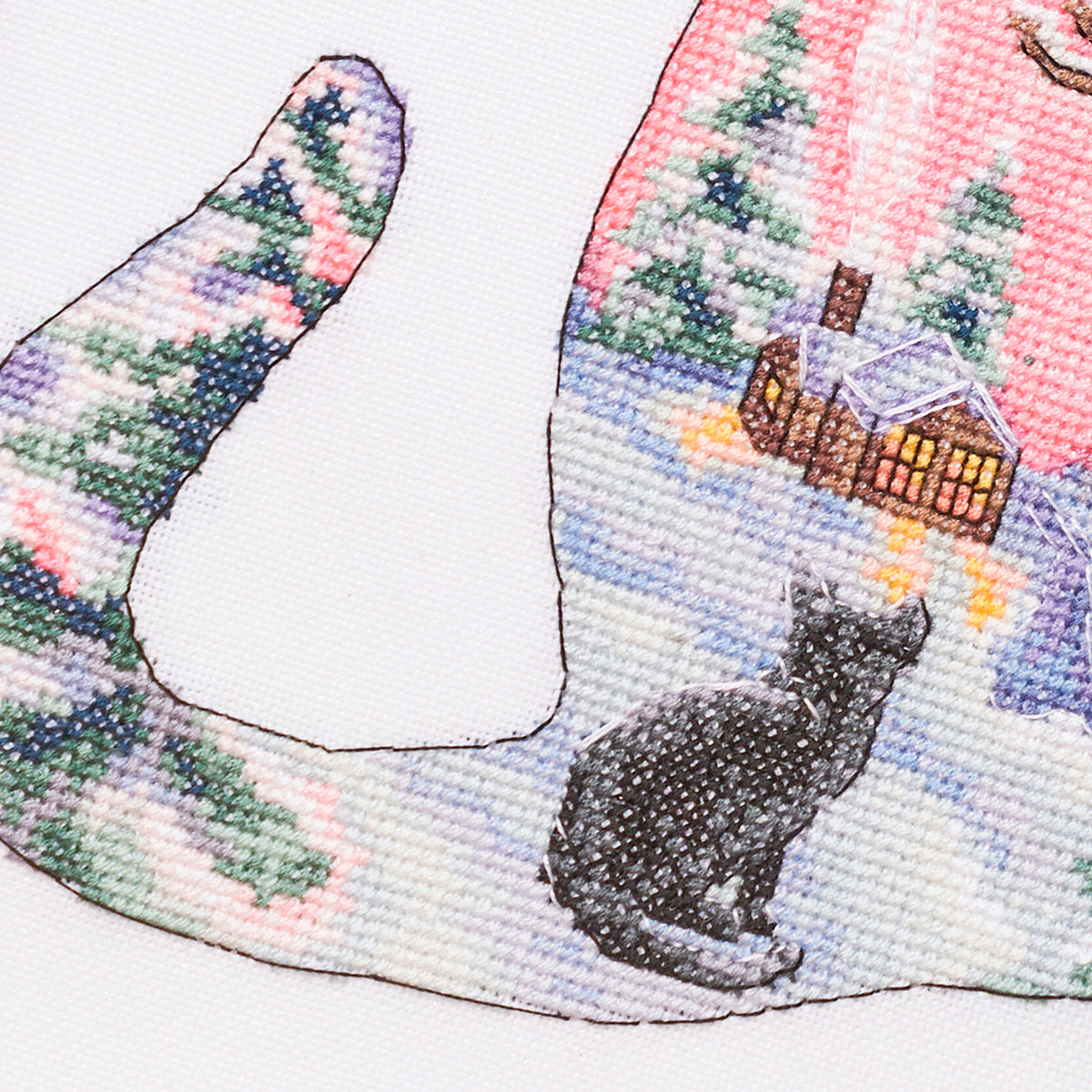 Cross-stitched design of a cat sitting on a snow-covered landscape with a house in the background.