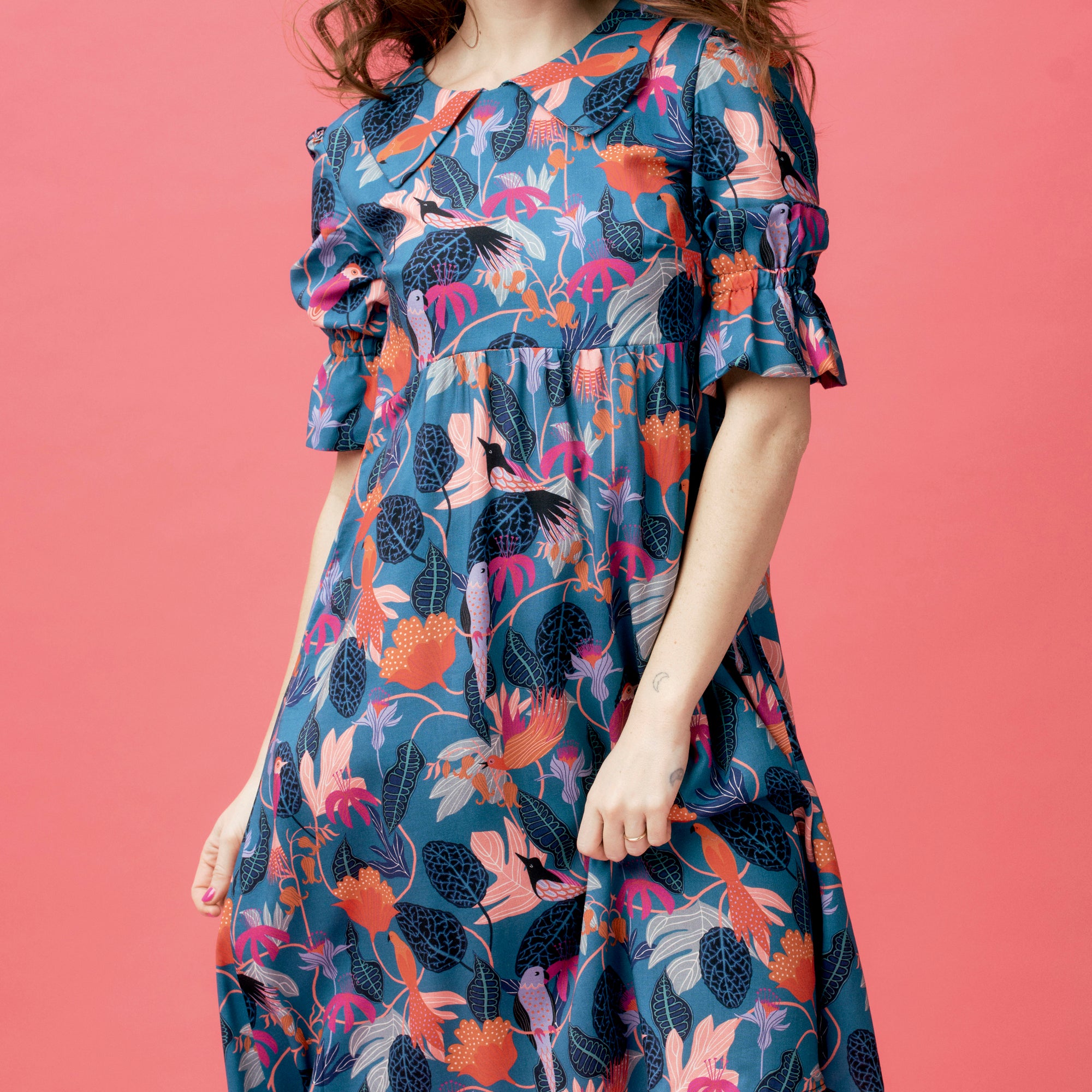 Woman wearing a floral dress against a pink background