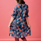 Woman wearing a colorful floral dress against a pink background