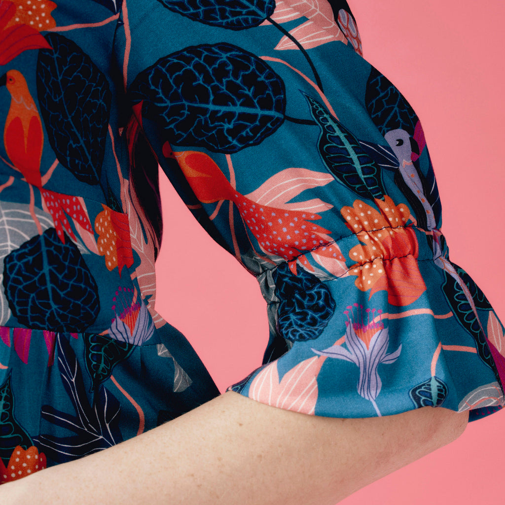 Colorful floral and bird patterned fabric on a pink background
