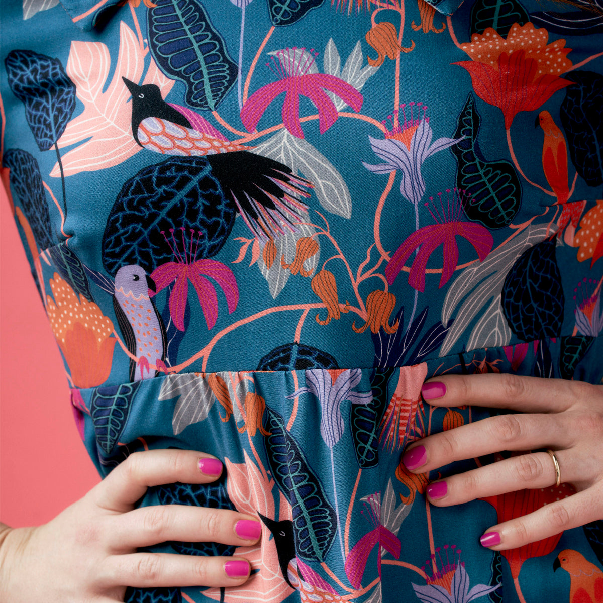 Person holding a fabric with a colorful floral and bird pattern.
