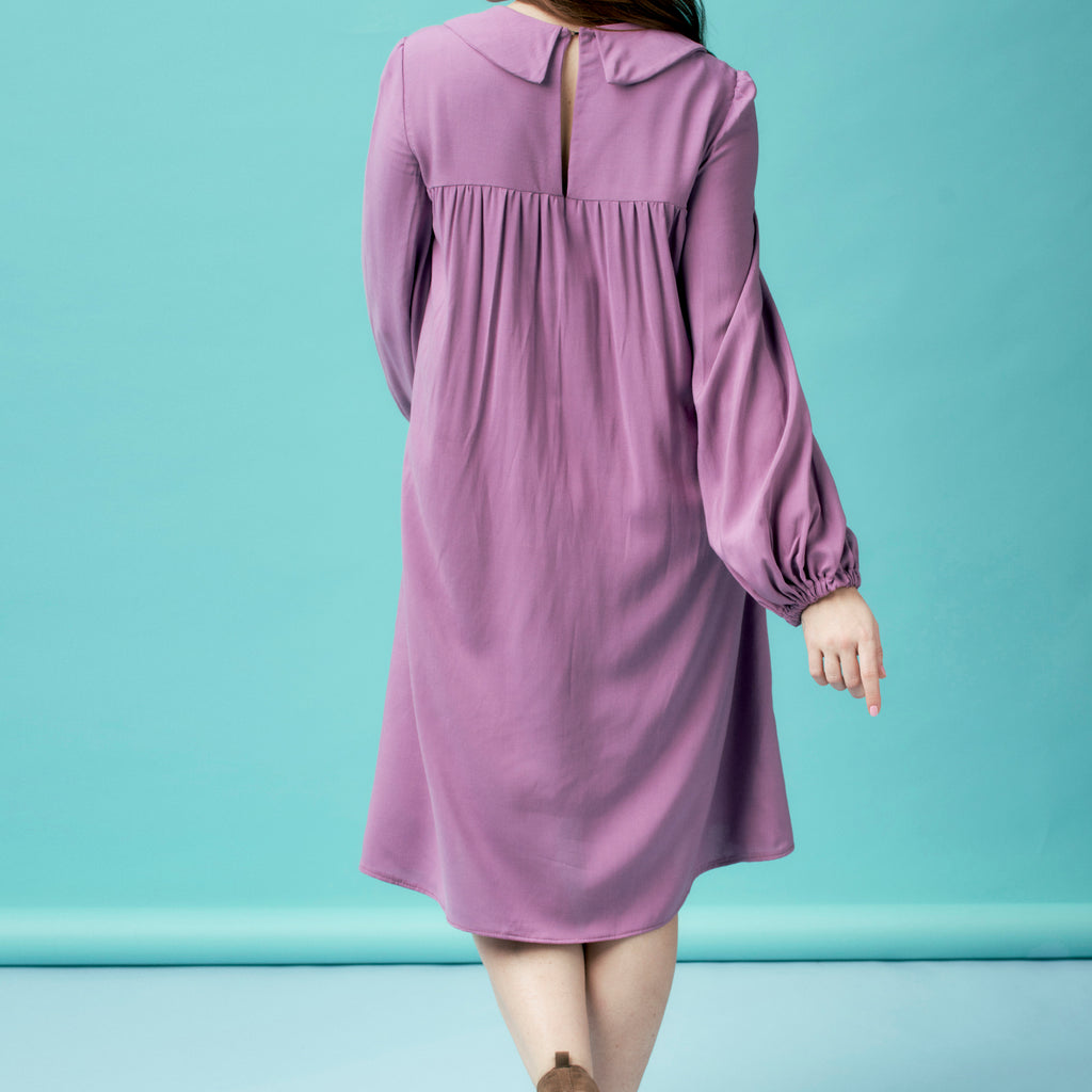Purple dress with long sleeves on a person against a light blue background