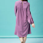 Purple dress with long sleeves on a person against a light blue background