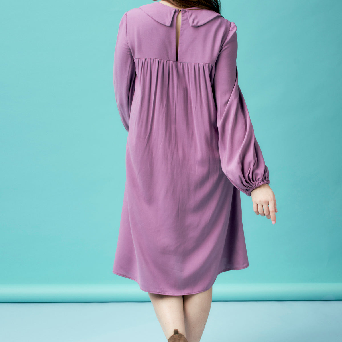 Purple dress with long sleeves on a person against a light blue background
