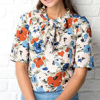 Woman wearing a floral blouse with a white brick wall background