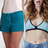Crocheted teal shorts on one side and a blue and black crochet top on the other, with a person wearing jeans.
