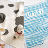 Two baby blankets, one with a dog design and the other with 'LITTLE 1' text, on a white surface.