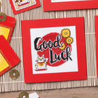 Cross-stitched design with 'Good Luck' text and a cat on a red background, surrounded by decorative items.
