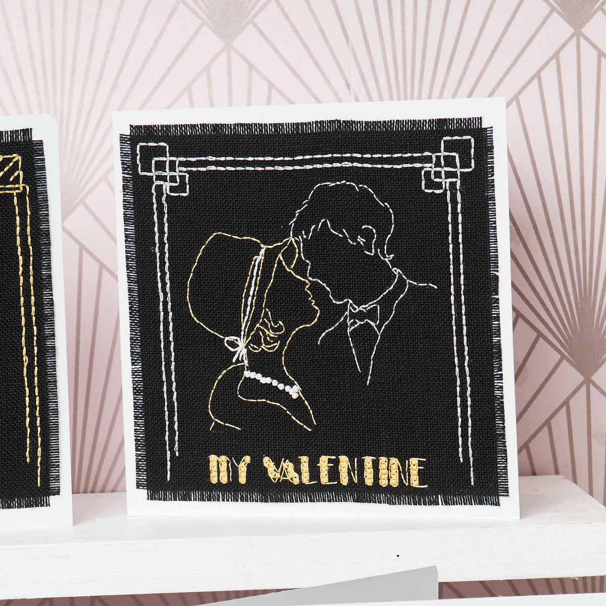 Embroidered card with a couple embracing and 'My Valentine' text on a geometric patterned background.