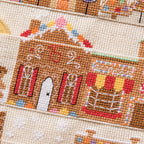 Close-up of a cross-stitched gingerbread house design on fabric.