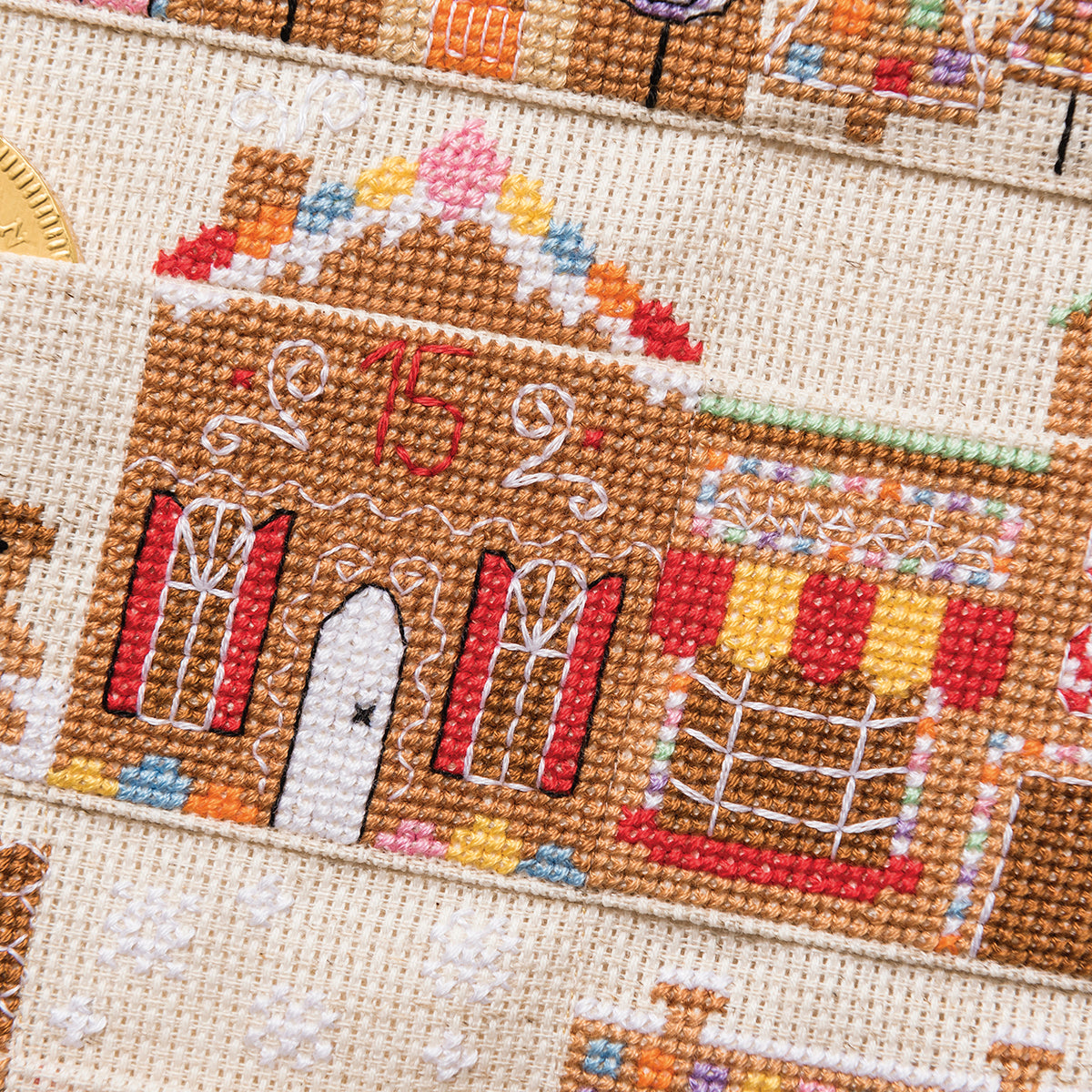 Close-up of a cross-stitched gingerbread house design on fabric.
