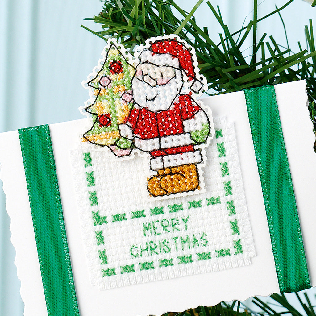 Cross-stitched Christmas ornament with Santa Claus and tree on a white background