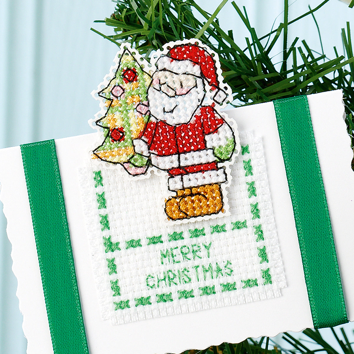 Cross-stitched Christmas ornament with Santa Claus and tree on a white background