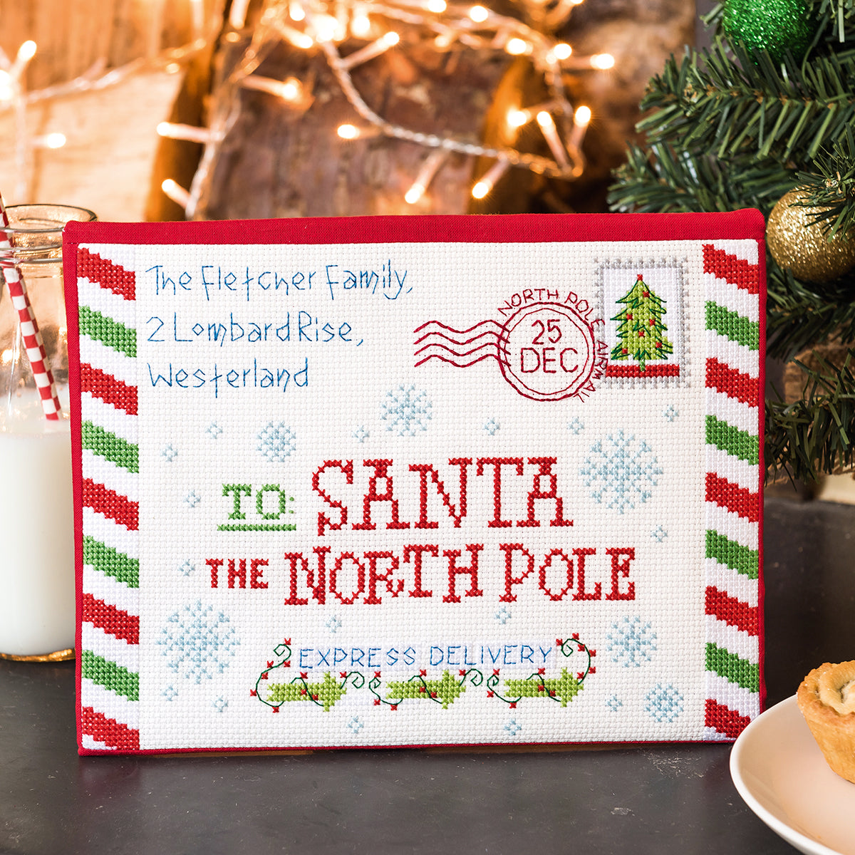 Cross-stitched letter to Santa with festive design on a Christmas-themed background